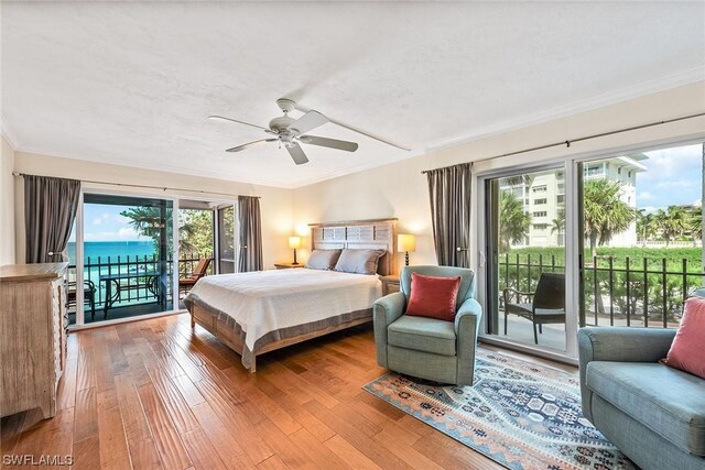 bedroom with hardwood / wood-style flooring, ceiling fan, access to exterior, a water view, and ornamental molding