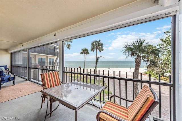 sunroom with a water view, a wealth of natural light, and a beach view