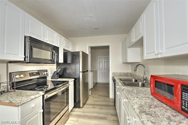 kitchen featuring stainless steel electric range oven, built in microwave, light hardwood / wood-style flooring, white cabinetry, and sink