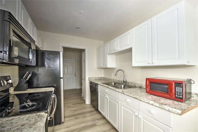 kitchen featuring sink, black dishwasher, light hardwood / wood-style floors, electric range oven, and white cabinetry