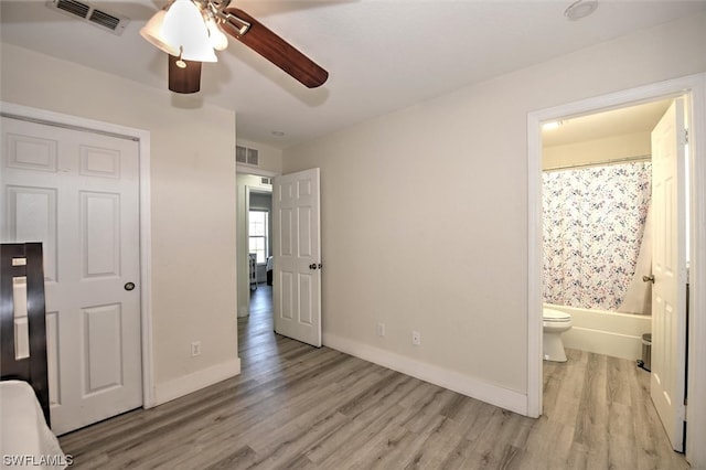 bedroom with ensuite bath, light hardwood / wood-style floors, and ceiling fan