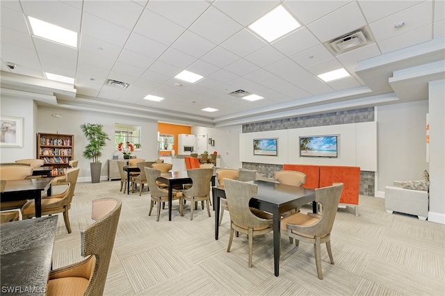 carpeted dining area featuring a paneled ceiling