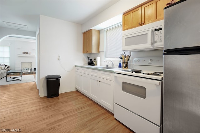 2147 Washington Ave, Naples, FL 34112 - kitchen with a fireplace, white appliances, sink, light wood-type flooring, and white cabinets