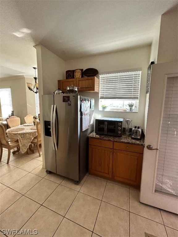 kitchen featuring light tile flooring, stainless steel refrigerator with ice dispenser, and dark stone countertops