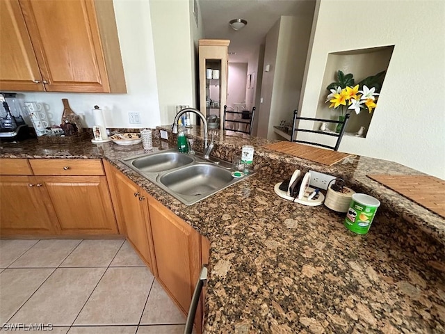 kitchen with sink, light tile flooring, and dark stone counters