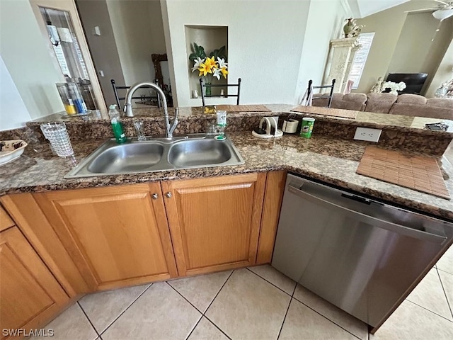 kitchen with sink, dark stone countertops, light tile flooring, and dishwasher