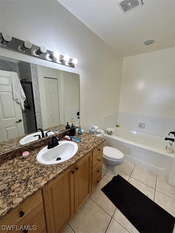 bathroom featuring a bathtub, tile flooring, vanity with extensive cabinet space, and toilet