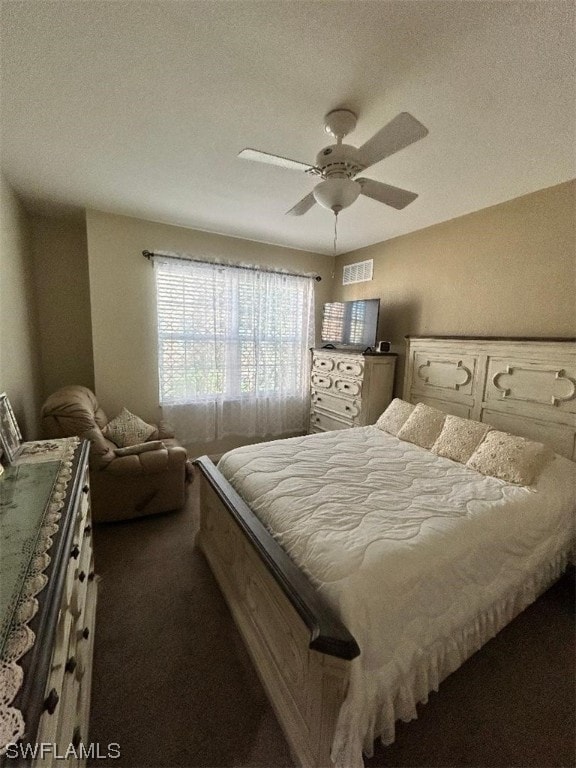 bedroom featuring a textured ceiling, dark colored carpet, and ceiling fan