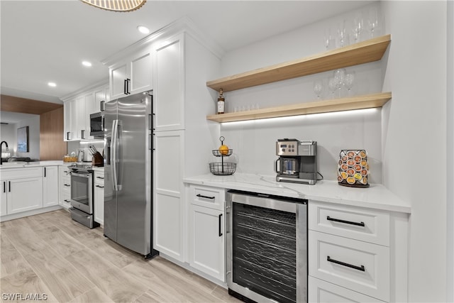 kitchen with wine cooler, light hardwood / wood-style flooring, appliances with stainless steel finishes, white cabinetry, and light stone counters