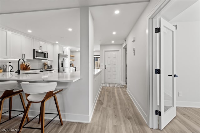 kitchen featuring light hardwood / wood-style floors, stainless steel appliances, white cabinets, and kitchen peninsula