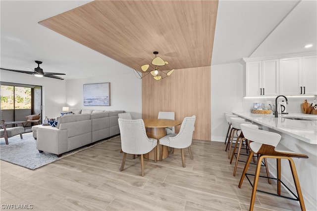 dining area featuring ceiling fan with notable chandelier and sink