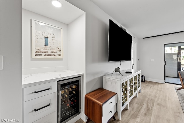 interior space featuring beverage cooler, light hardwood / wood-style floors, and indoor bar