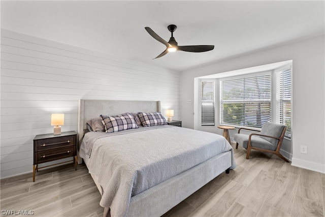 bedroom featuring wooden walls, ceiling fan, and light hardwood / wood-style flooring