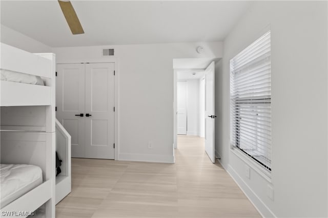 bedroom with a closet, light hardwood / wood-style floors, and ceiling fan