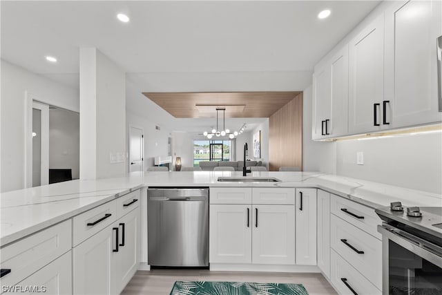 kitchen featuring sink, a chandelier, light hardwood / wood-style flooring, stainless steel appliances, and light stone countertops