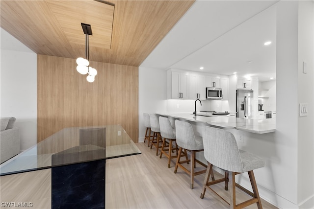 dining space featuring wooden ceiling, sink, and light wood-type flooring