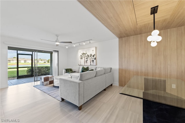 tiled living room with wood walls, wood ceiling, rail lighting, and ceiling fan with notable chandelier