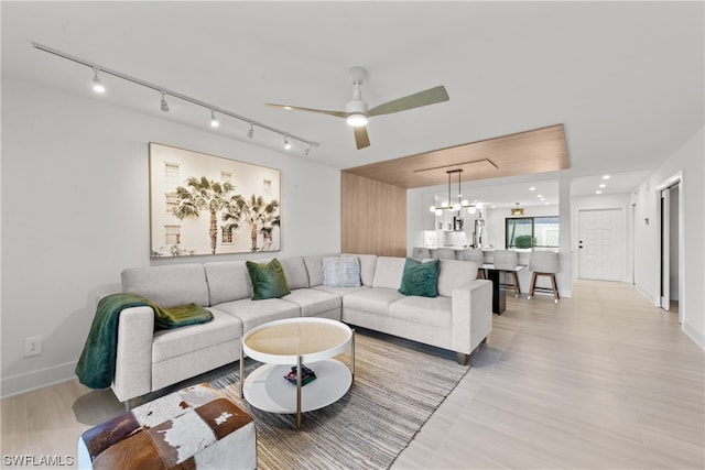 living room featuring rail lighting and ceiling fan with notable chandelier