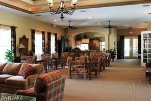 carpeted dining area featuring ceiling fan with notable chandelier and french doors