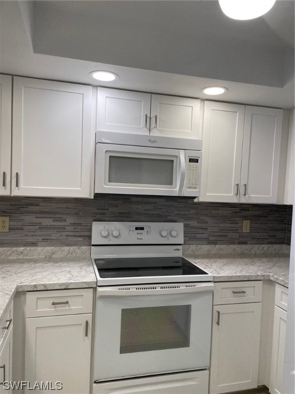 kitchen with white appliances, white cabinetry, and tasteful backsplash