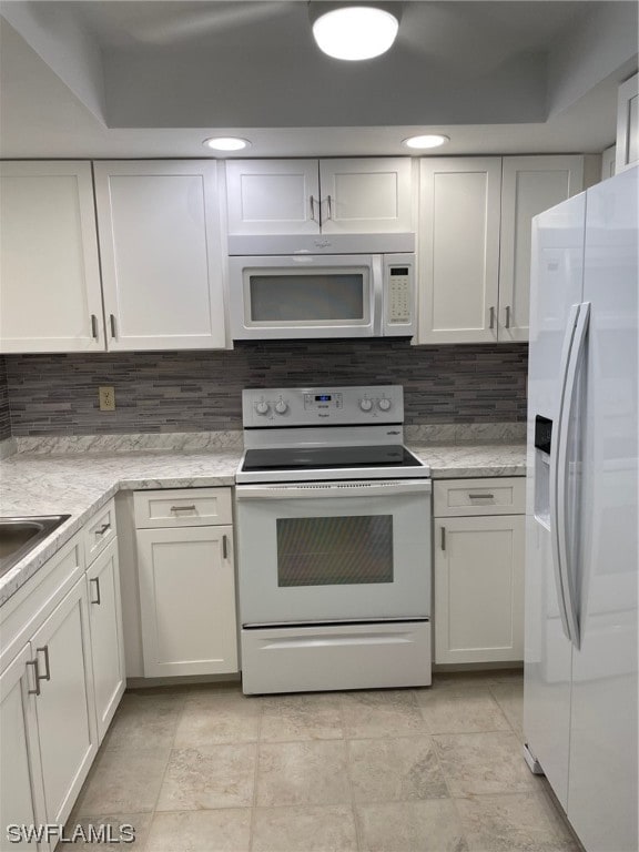 kitchen featuring tasteful backsplash, white appliances, white cabinetry, and light tile floors