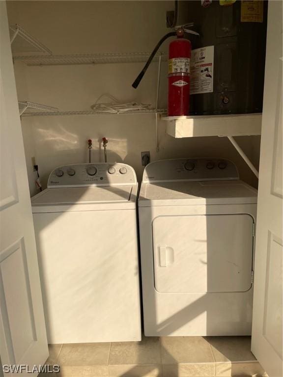 clothes washing area with laundry area, tile patterned flooring, and washer and clothes dryer