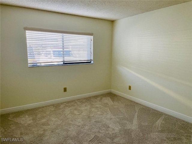 carpeted spare room featuring a textured ceiling and baseboards