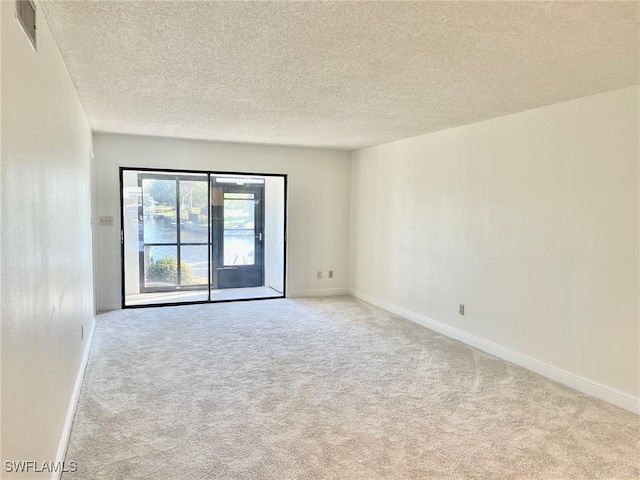 carpeted empty room featuring visible vents, a textured ceiling, and baseboards