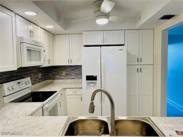 kitchen with white appliances, white cabinetry, visible vents, and a sink