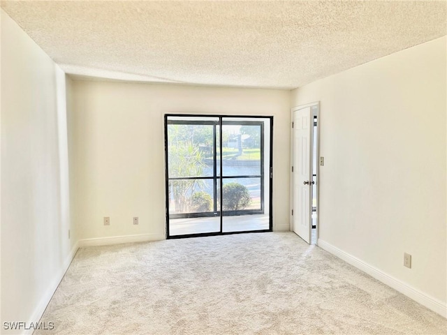 carpeted spare room featuring baseboards and a textured ceiling