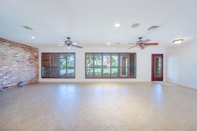 empty room featuring brick wall, ceiling fan, and light tile flooring