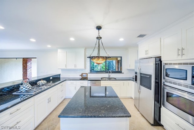 kitchen featuring hanging light fixtures, dark stone countertops, appliances with stainless steel finishes, white cabinets, and sink