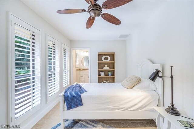 bedroom featuring ensuite bath, ceiling fan, tile floors, and multiple windows