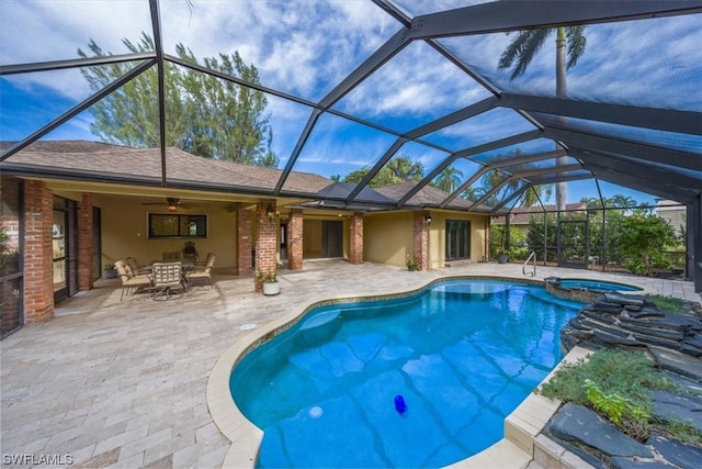 view of pool with a patio, glass enclosure, and ceiling fan