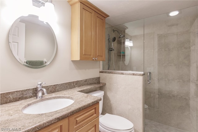 bathroom featuring an enclosed shower, tile walls, toilet, and vanity