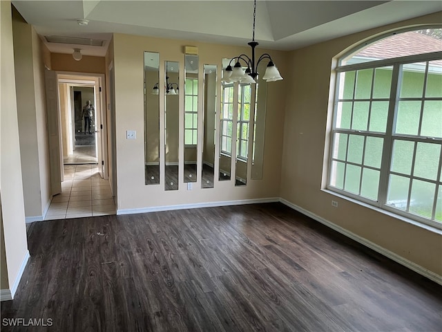 unfurnished dining area featuring dark hardwood / wood-style floors, plenty of natural light, and a notable chandelier