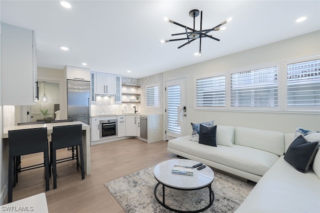 living room with ceiling fan, sink, and light hardwood / wood-style floors