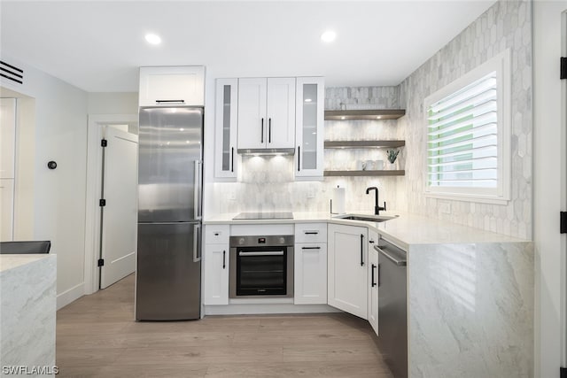 kitchen with sink, stainless steel appliances, light wood-type flooring, and white cabinets