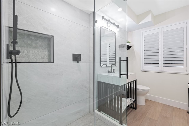 bathroom with hardwood / wood-style flooring, toilet, vanity, and a tile shower