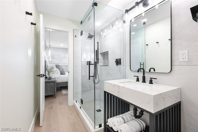 bathroom featuring wood-type flooring, a shower with shower door, and vanity with extensive cabinet space