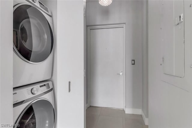 laundry area featuring electric panel, stacked washer and dryer, and light tile patterned flooring