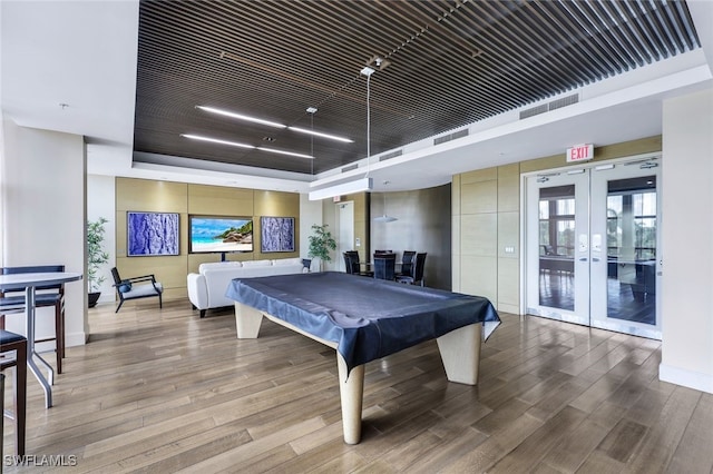 game room featuring french doors, billiards, a raised ceiling, and hardwood / wood-style floors