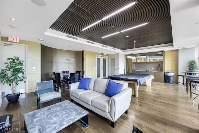 game room featuring a tray ceiling, wood-type flooring, and billiards