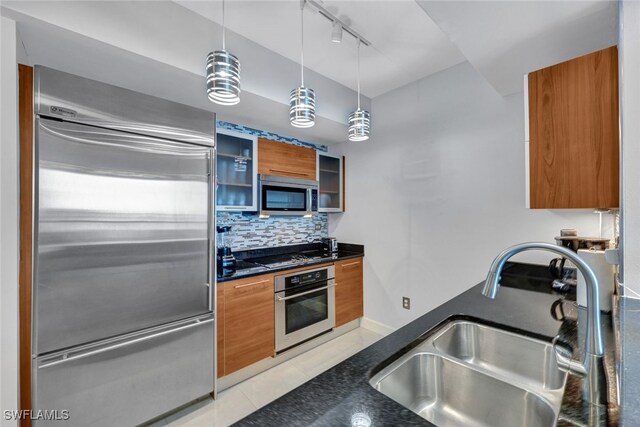 kitchen featuring rail lighting, hanging light fixtures, sink, light tile patterned floors, and appliances with stainless steel finishes