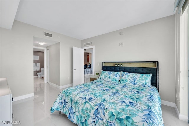 bedroom with ensuite bathroom and light tile patterned floors