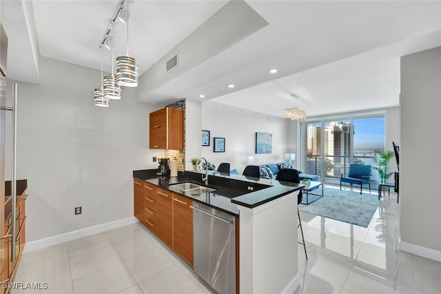 kitchen featuring kitchen peninsula, pendant lighting, sink, and stainless steel dishwasher