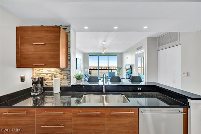 kitchen with stainless steel dishwasher, dark stone countertops, sink, and tasteful backsplash