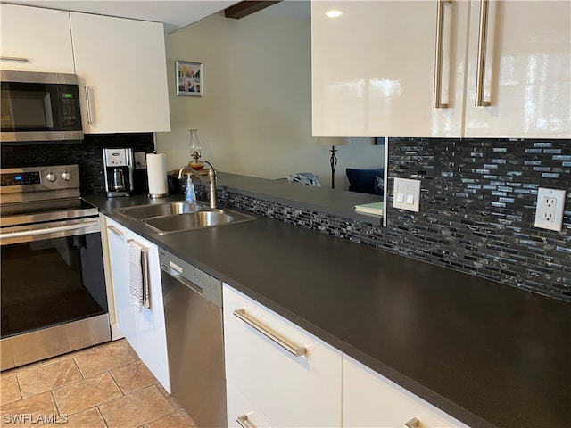 kitchen featuring sink, white cabinets, stainless steel appliances, light tile flooring, and tasteful backsplash