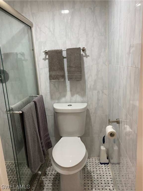 bathroom featuring tile walls, toilet, and tile flooring