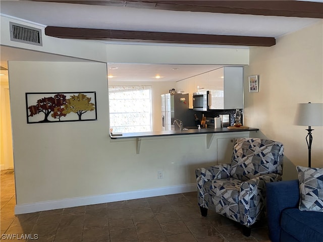 sitting room featuring dark tile flooring and beamed ceiling